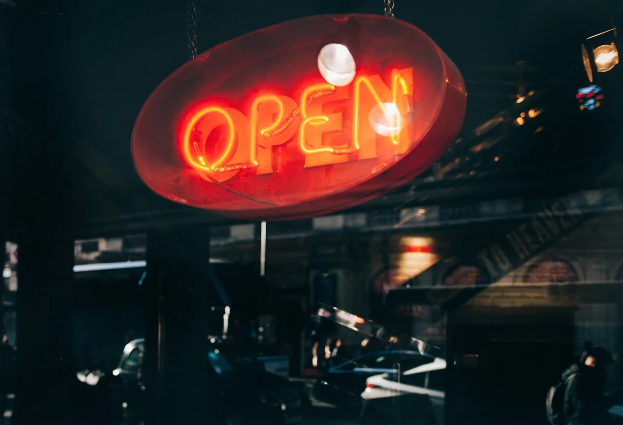 Illuminated red neon "OPEN" shop sign hanging in a storefront window at night